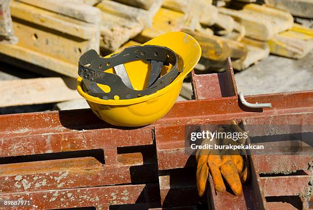 vista del casco duro y guantes en solar de construcción - colisionar fotografías e imágenes de stock