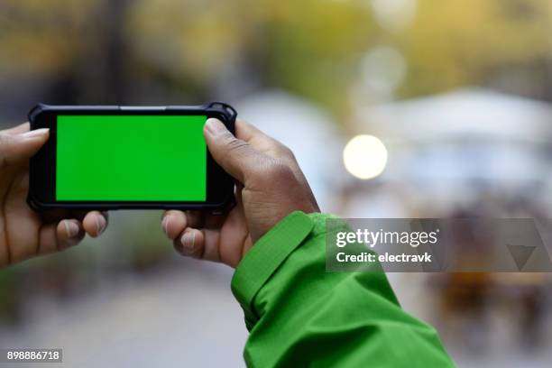 man holding smartphone with green screen - green screen stock pictures, royalty-free photos & images