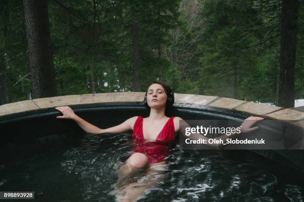 mujer escuchando música en auriculares inalámbricos en bañera de hidromasaje - bañera caliente fotografías e imágenes de stock