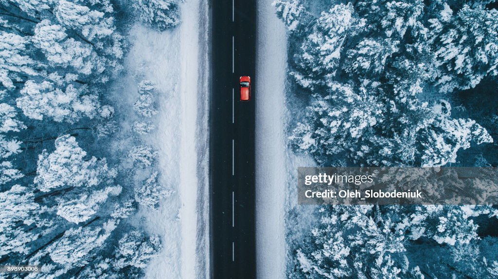 Aerial view of road in winter with red car on it