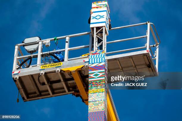 Man helps fix the top of a LEGO tower under construction in Tel Aviv on December 27 as the city attempts to break Guinness world record of the...