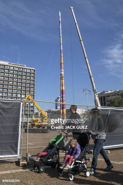 Couple push child strollers as they walk past a LEGO tower under construction in Tel Aviv's Rabin Square on December 27 as the city attempts to break...
