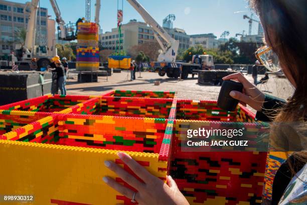 Woman assembles bricks as she works on a component of a LEGO tower under construction in Tel Aviv's Rabin Square on December 26 as the city attempts...