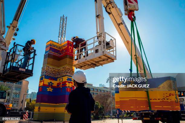 Workers and volunteers help assemble bricks during the construction of a LEGO tower in Tel Aviv's Rabin Square on December 26 as the city attempts to...