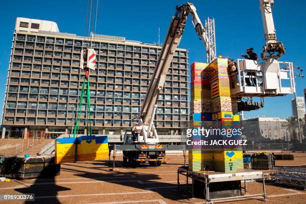 Workers and volunteers help assemble bricks during the construction of a LEGO tower in Tel Aviv's Rabin Square on December 26 as the city attempts to...