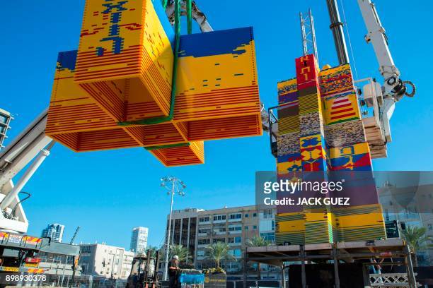 Workers and volunteers help assemble bricks during the construction of a LEGO tower in Tel Aviv's Rabin Square on December 26 as the city attempts to...