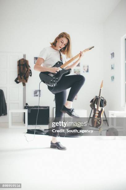 junge frau abgeschalt gitarre spielen - playing electric guitar stock-fotos und bilder