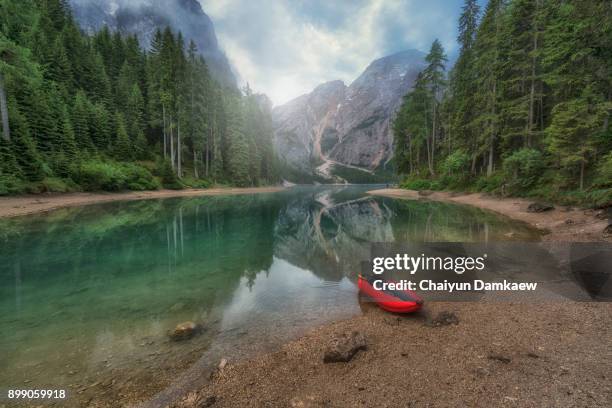 red kayak on the lake with mountain background. - gebirgskette latemar stock-fotos und bilder