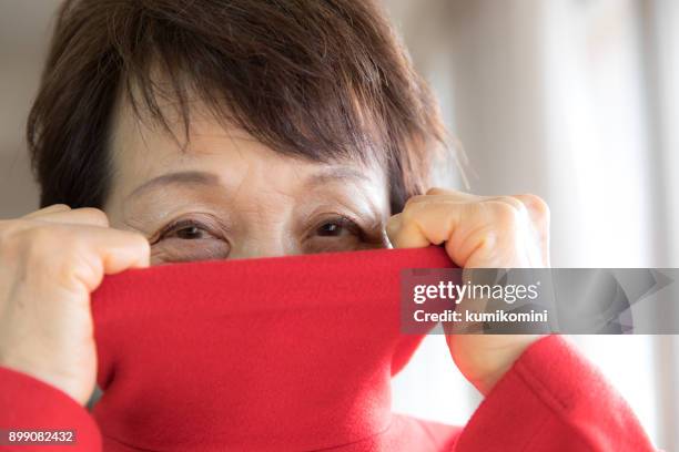 oude vrouw zetten rode trui - uitkleden stockfoto's en -beelden