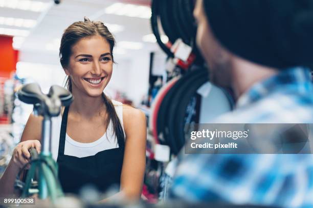 cheerful assistant in a bike shop - sports merchandise stock pictures, royalty-free photos & images