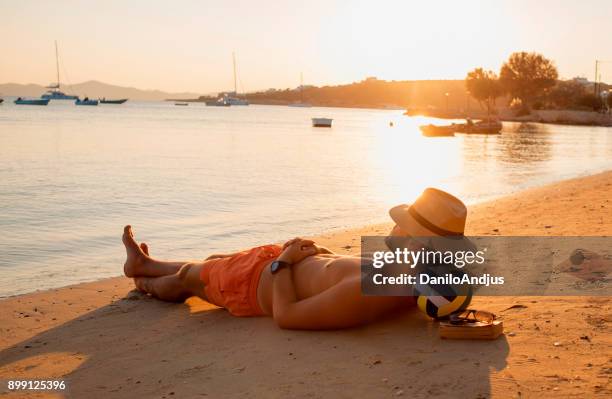hombre disfrutando del atardecer en la playa - tomar el sol fotografías e imágenes de stock