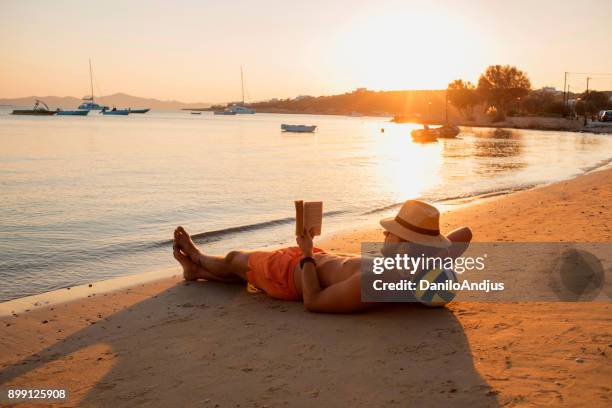 man genieten van de zonsondergang op het strand - beach book reading stockfoto's en -beelden