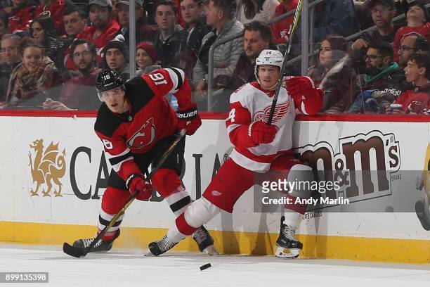 Steven Santini of the New Jersey Devils skates for the puck against Gustav Nyquist of the Detroit Red Wings during the game at Prudential Center on...