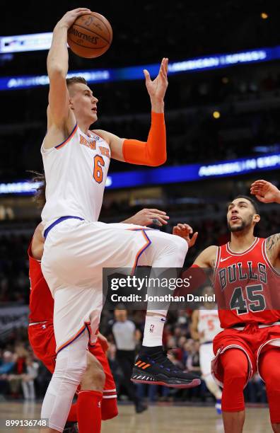 Kristaps Porzingis of the New York Knicks goes up for a dunk against Robin Lopez and Denzel Valentine of the Chicago Bulls at the United Center on...