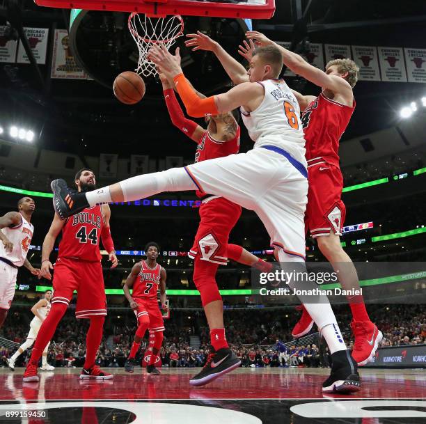 Kristaps Porzingis of the New York Knicks battles for a rebound with Denzel Valentine and Luari Markkanen of the Chicago Bulls at the United Center...