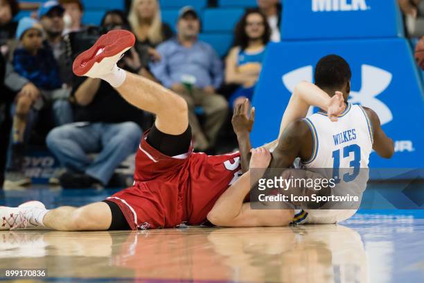 South Dakota Coyotes forward Nick Fuller gets tangled up with UCLA Bruins guard Kris Wilkes as they go to the ground during the game between the...
