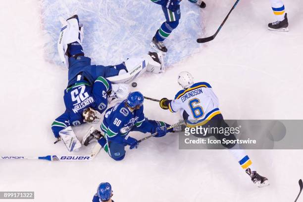 St. Louis Blues Defenceman Joel Edmundson reaches for a loose puck as Vancouver Canucks Goalie Jacob Markstrom stretches to cover the puck during...