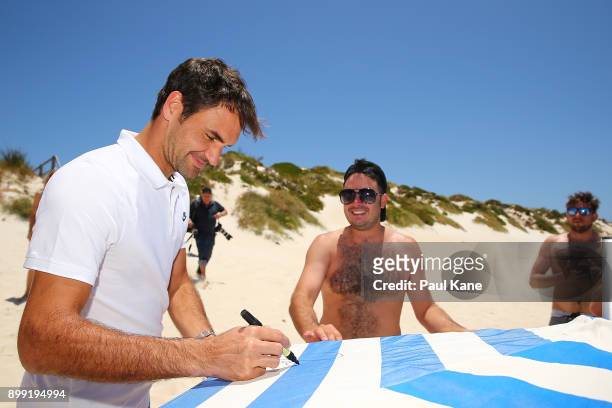 Roger Federer of Switzerland signs a beach umbrella for a beach goer at Rottnest Island ahead of the 2018 Hopman Cup on December 28, 2017 in Perth,...