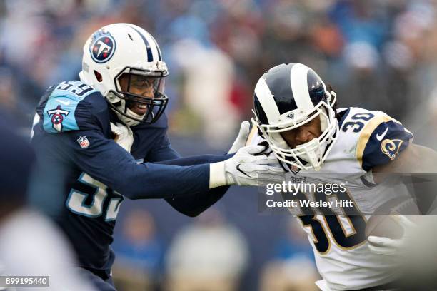 Todd Gurley II of the Los Angeles Rams runs the ball and is grabbed by Wesley Woodyard of the Tennessee Titans at Nissan Stadium on December 24, 2017...