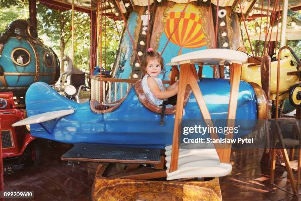 girl enjoying ride on carousel in airplane - carousel foto e immagini stock