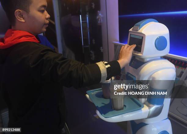 This picture taken on December 11, 2017 shows a waiter programming a robot named "Mortar" to deliver ordered drinks to customers at the Robo Cafe,...