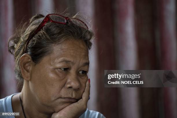 Maria Espinosa listens to a prayer before she and other relatives visit the grave of their loved ones, all minors, who were killed a year ago during...
