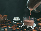 Pouring tasty cocoa drink into mug on table