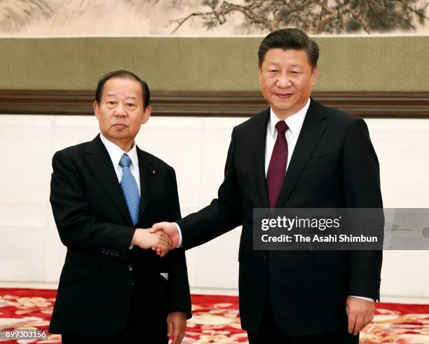 Ruling Liberal Democratic Party secretary general Toshihiro Nikai and Chinese President Xi Jinping shake hand during their meeting at the Great Hall...