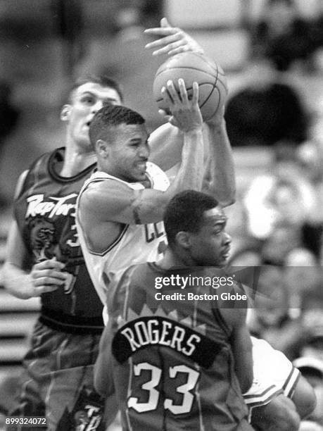 Boston Celtics Dana Barros, center, receives pressure from Toronto Raptors Zan Tabak, left, and Carlos Rogers, right, during a game at the Boston...