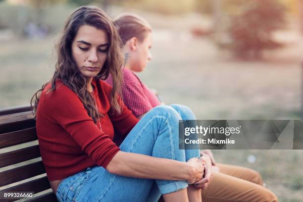 vrouwen zitten verdrietig en ver van elkaar verwijderd - lesbische stockfoto's en -beelden