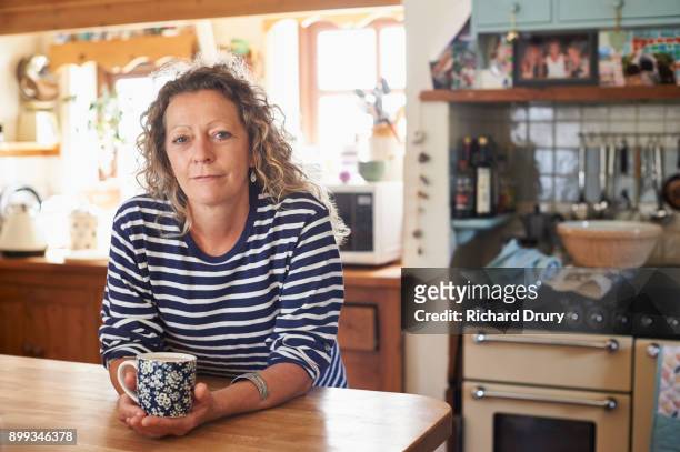 woman holding mug of tea - vrouw 50 jaar stockfoto's en -beelden