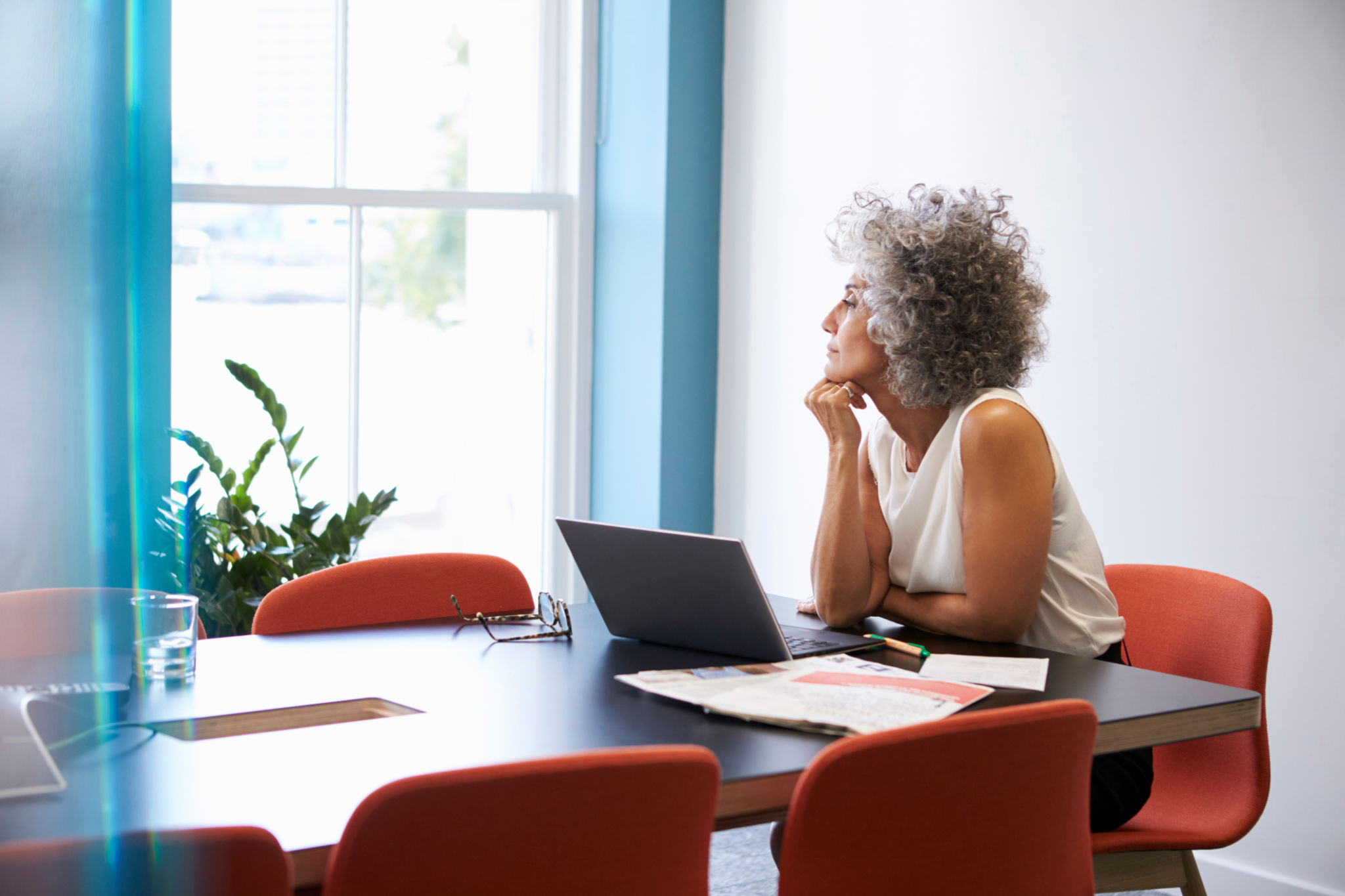 Middle aged woman looking out of the window in the boardroom Middle aged woman looking out of the window in the boardroom