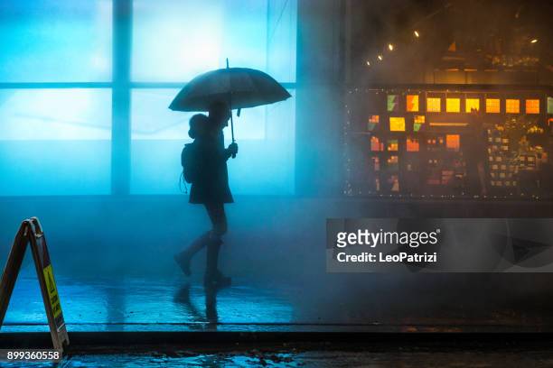 Foggy downtown in Lower Manhattan a woman walking under the rain in the dark