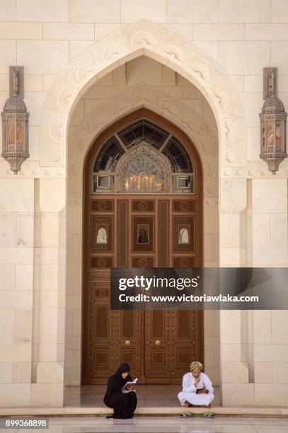 two people reading at sultan qaboos grand mosque grounds - reading v oman stock-fotos und bilder