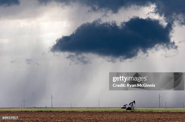 oil field dark clouds rain - derrick photos et images de collection