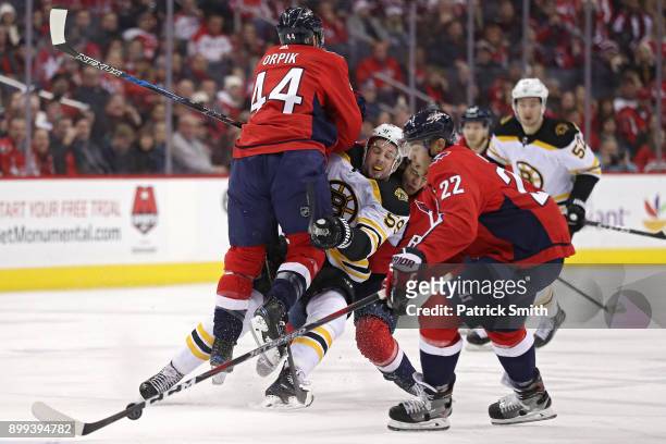Tim Schaller of the Boston Bruins is checked by Brooks Orpik of the Washington Capitals during the first period at Capital One Arena on December 28,...