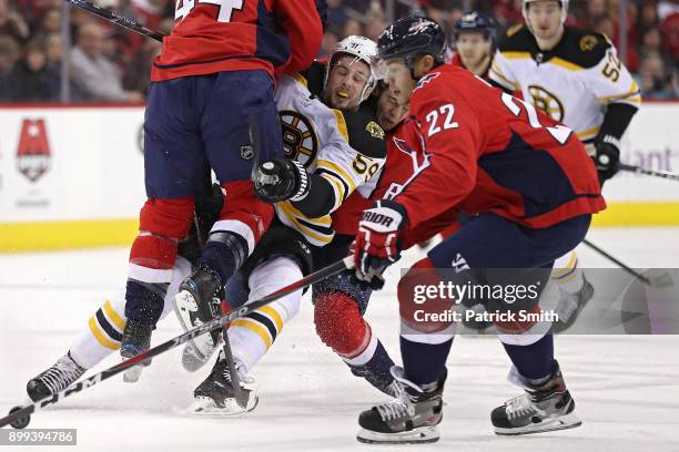 Tim Schaller of the Boston Bruins is checked by Brooks Orpik of the Washington Capitals during the first period at Capital One Arena on December 28,...