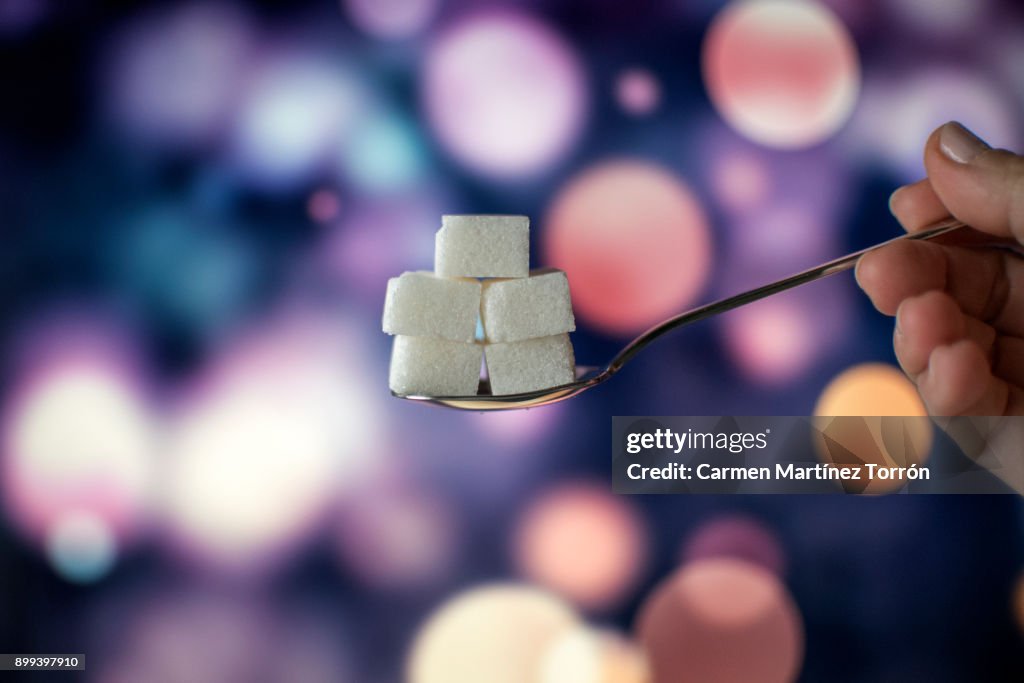 Sugar cubes on teaspoon.