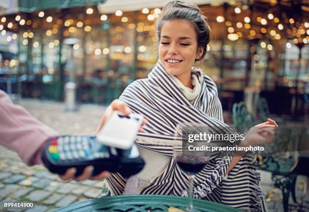 jeune femme boit du vin et payer avec son téléphone mobile - bar paris photos et images de collection