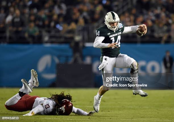 Michigan State Brian Lewerke leaps and escapes the grasp of Washington State Jahad Woods during the Holiday Bowl game between the Washington State...