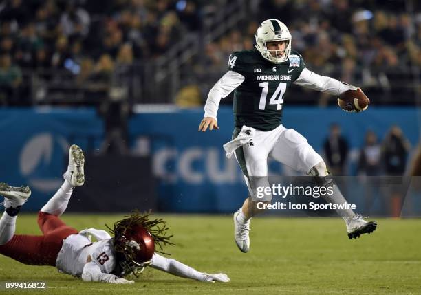 Michigan State Brian Lewerke leaps and escapes the grasp of Washington State Jahad Woods during the Holiday Bowl game between the Washington State...