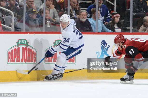 Auston Matthews of the Toronto Maple Leafs skates with the puck as Lawson Crouse of the Arizona Coyotes defends during the second period at Gila...