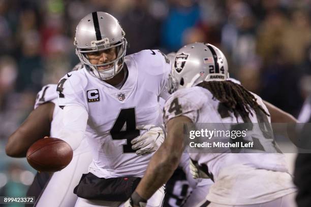 Derek Carr of the Oakland Raiders hands the ball off to Marshawn Lynch against the Philadelphia Eagles at Lincoln Financial Field on December 25,...