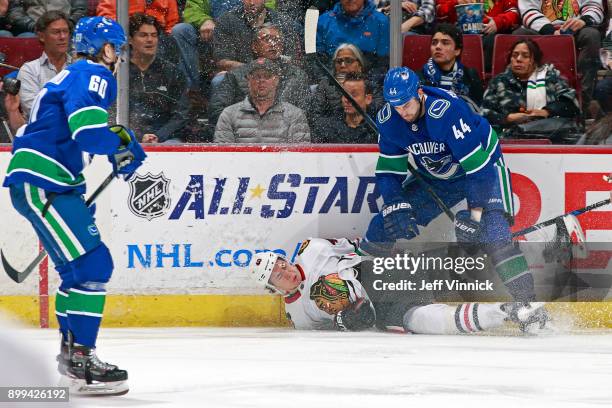 Erik Gudbranson of the Vancouver Canucks checks John Hayden of the Chicago Blackhawks during their NHL game at Rogers Arena December 28, 2017 in...