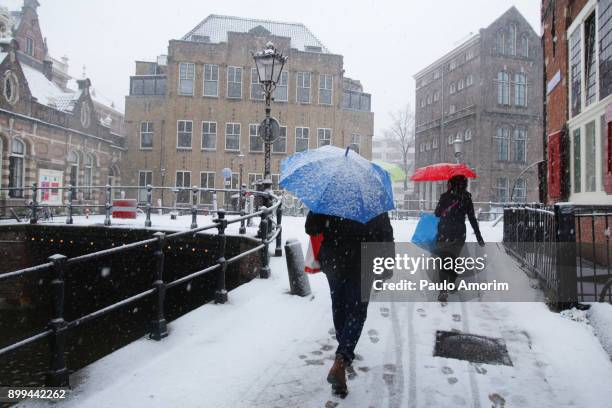 people walking on the street covered in snow in amsterdam - clima stock pictures, royalty-free photos & images