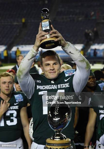 Michigan State Spartans quarterback Brian Lewerke lifts the offensive MVP Trophy on the field after the Spartans defeated the Washington State...