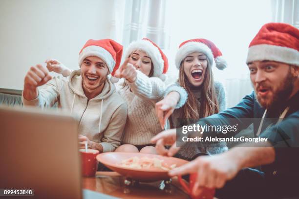 group of excited friend drink hot drink and watch interesting football game for the holidays - christmas movie stock pictures, royalty-free photos & images