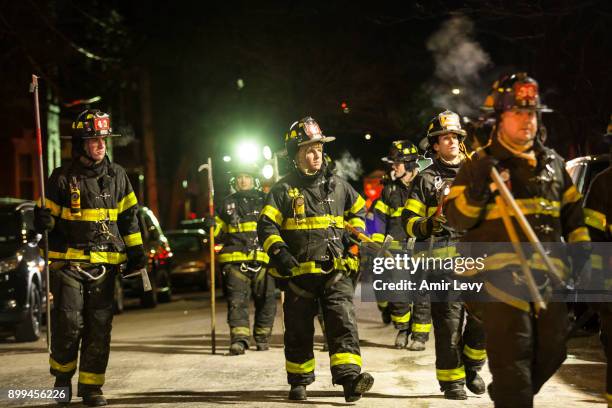 Firefighters leave after putting out a major house fire on Prospect avenue on December 28, 2017 in the Bronx borough of New York City. Over 170...