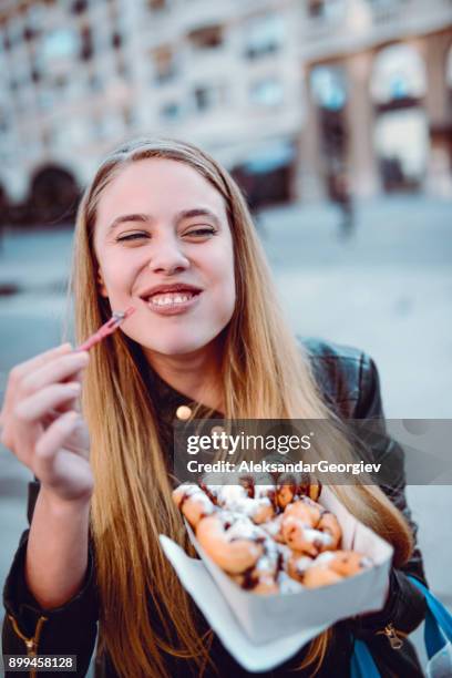 cute female with full mouth of donuts on fair in town square - desire stock pictures, royalty-free photos & images