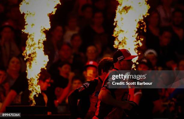 Aaron Finch and Brad Hogg of the Renegades run onto the field with their teammates through flames during the Big Bash League match between the...